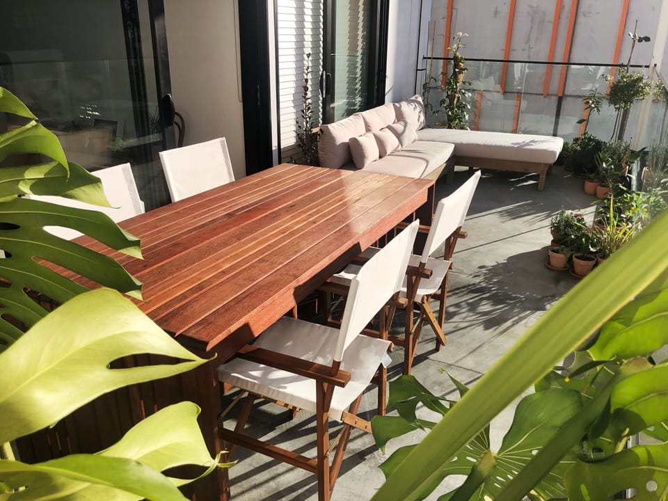 Hardwood dining table and director's chairs with the outdoor sofa and lounger.