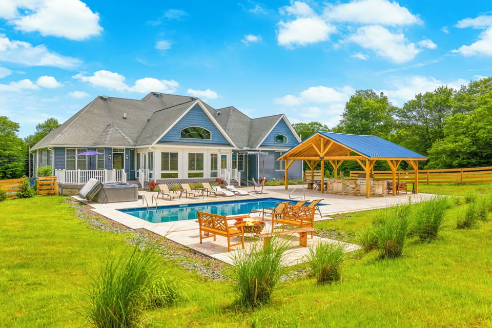 Patio area with a heated pool, outdoor kitchen and pavilion.