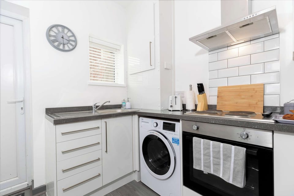Prepare meals in the bright, modern kitchen, featuring fitted appliances, a washing machine and ample worktop space.