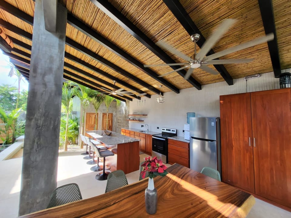 Stunning open-air kitchen and dining area, surrounded by lush greenery.