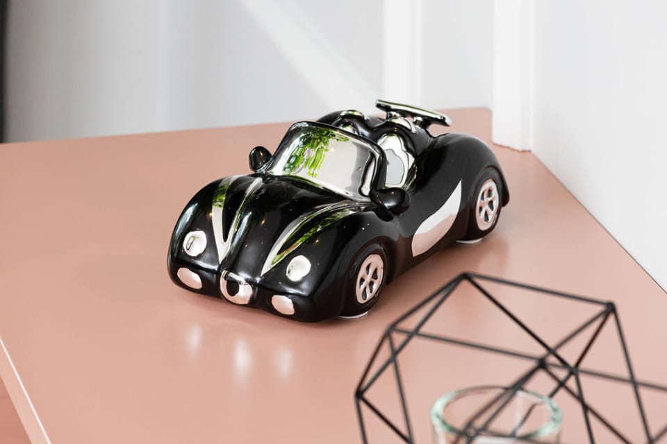 A toy car sits on a pink table, possibly part of a child’s play area or decor.