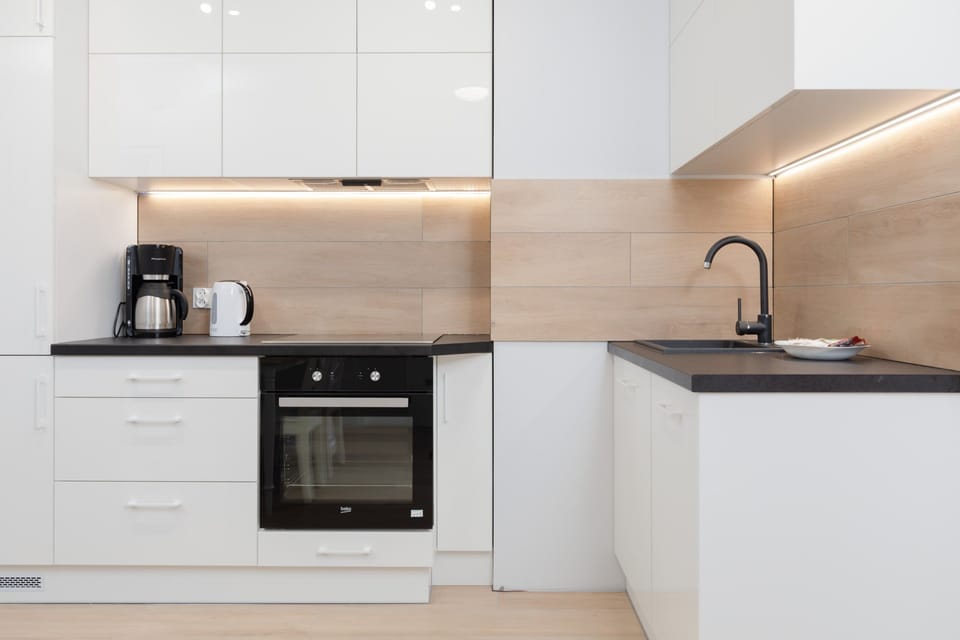 A modern kitchen with white cabinetry, a sleek black countertop, and essential appliances.
