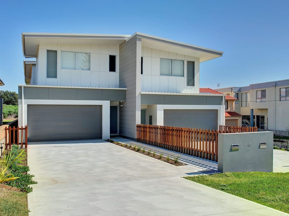 Modern duplex with garages, bright curb appeal, and sleek design