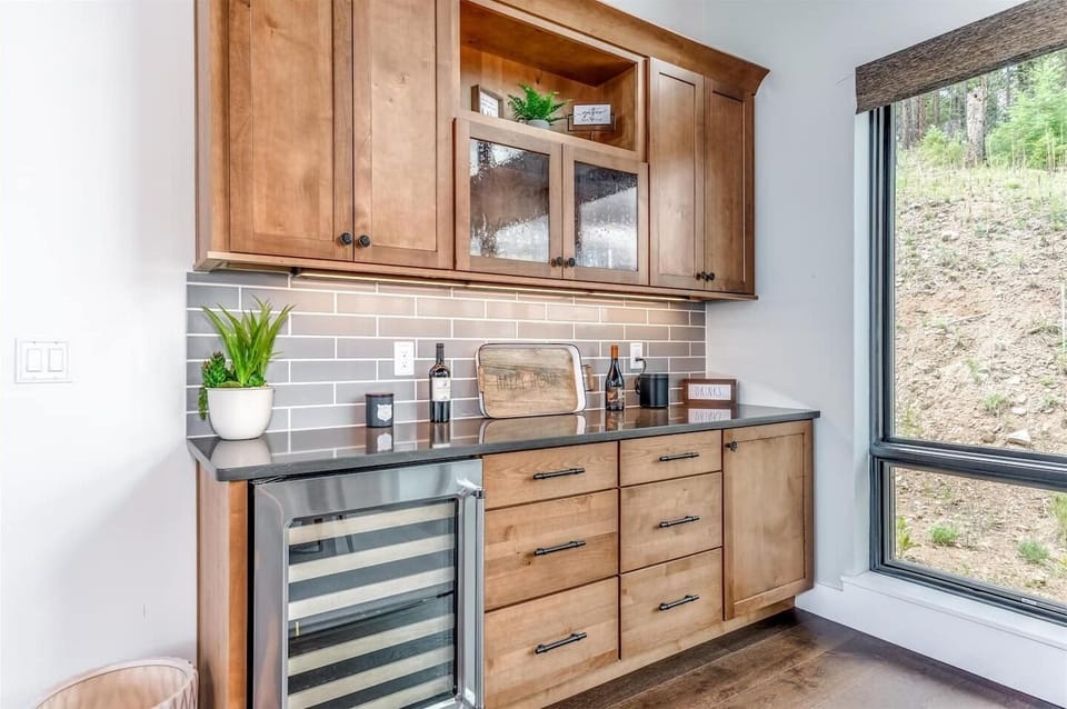 - Entertain with ease at the custom wet bar featuring a wine fridge and glass cabinetry
- Wood cabinets, subway tile backsplash, and curated accessories elevate the space
- Perfect for cocktails, mocktails, or a quiet evening glass of wine