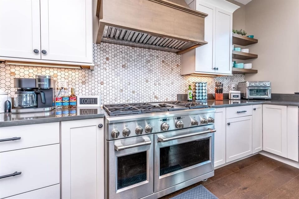 - Cook like a pro with this commercial grade gas range and stylish tile backsplash
- Six burners, dual ovens, and a wide vent hood make group meals a breeze
- Surrounded by sleek counters and custom cabinetry for form and function