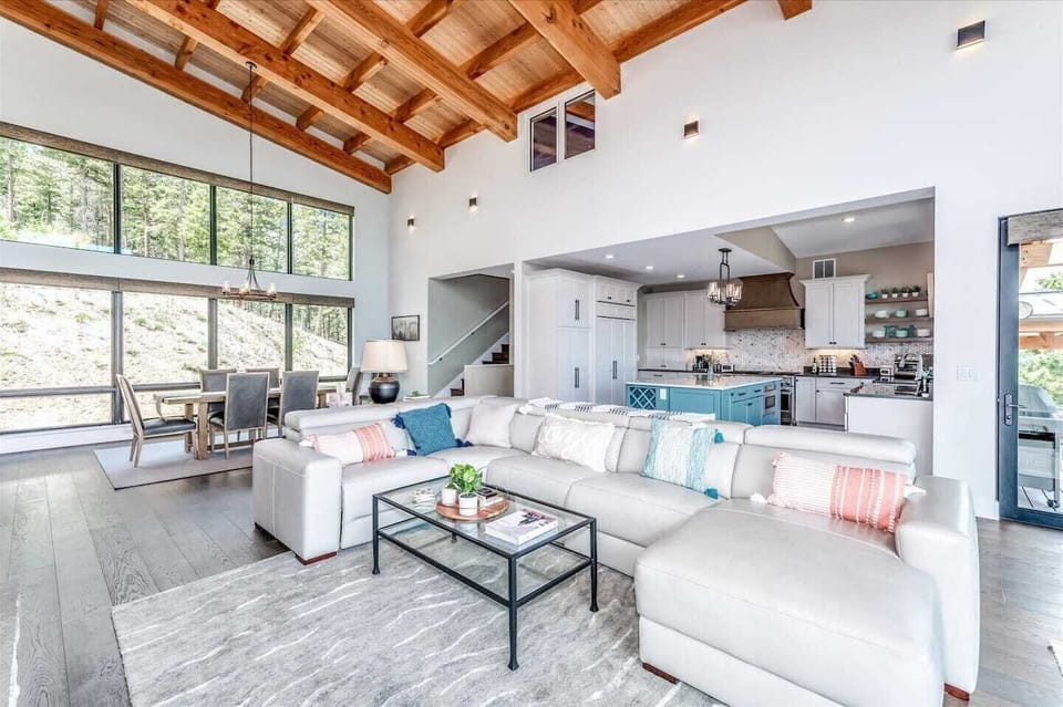 - Soaring wood beam ceilings and huge windows fill the space with natural light
- Lounge in style on a spacious sectional with soft pillows and forest views
- Open concept design flows seamlessly from kitchen to dining area

