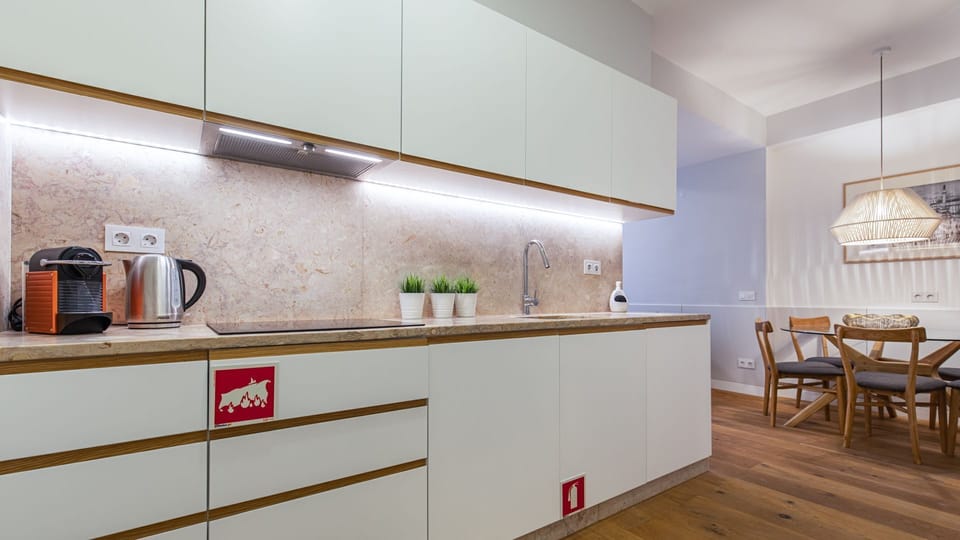 Prepare delightful meals in this sleek, modern kitchen, featuring pristine countertops and ample under-cabinet lighting, then gather around the inviting dining table for shared moments and delicious food. Enjoy the convenience of home cooking and memorabl