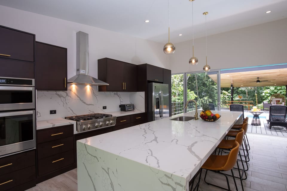 Open Plan Living Room + Chefs Kitchen, with glass walls to deck and jungle.