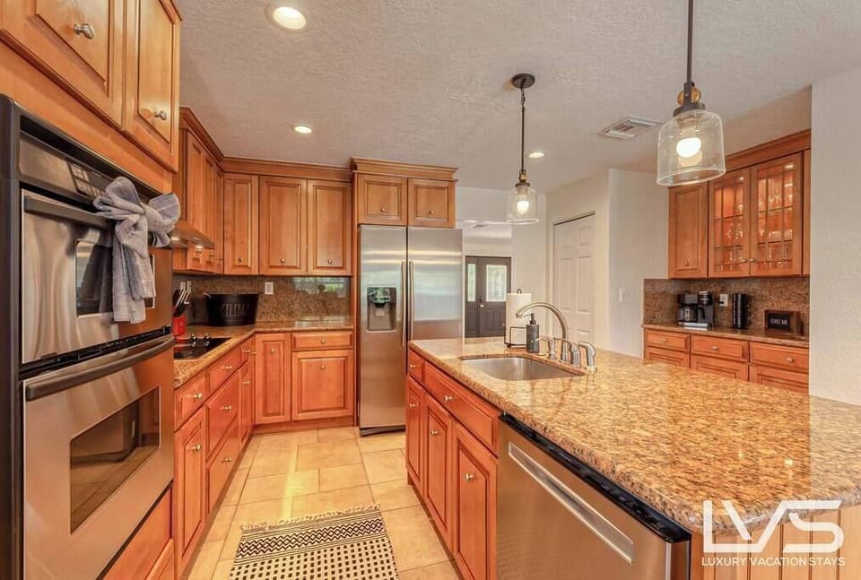 Open layout stocked kitchen with double oven, cooktop, full size refrigerator with ice maker & water dispenser & coffee bar.