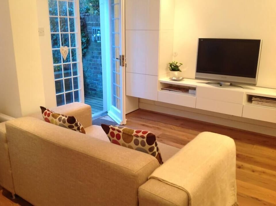large studio room with sofa separating the bed area. French doors open onto the private sunny garden