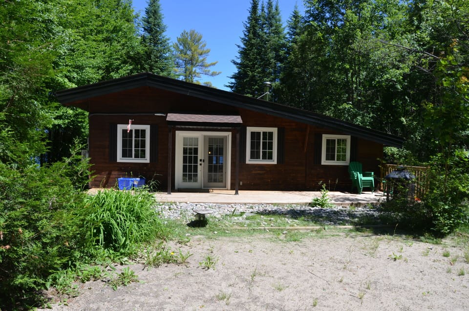 front of cottage with sandy volleyball/sports court & deck