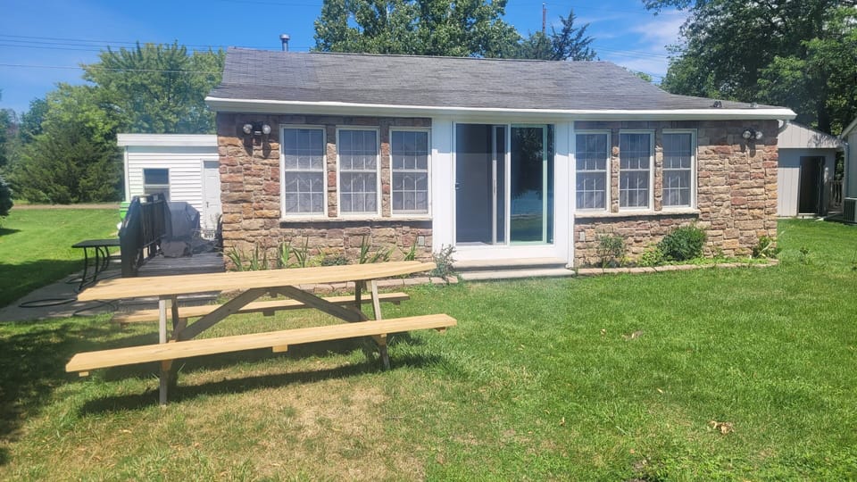 Lakeside view of the cottage with 8' long picnic table on the grass.