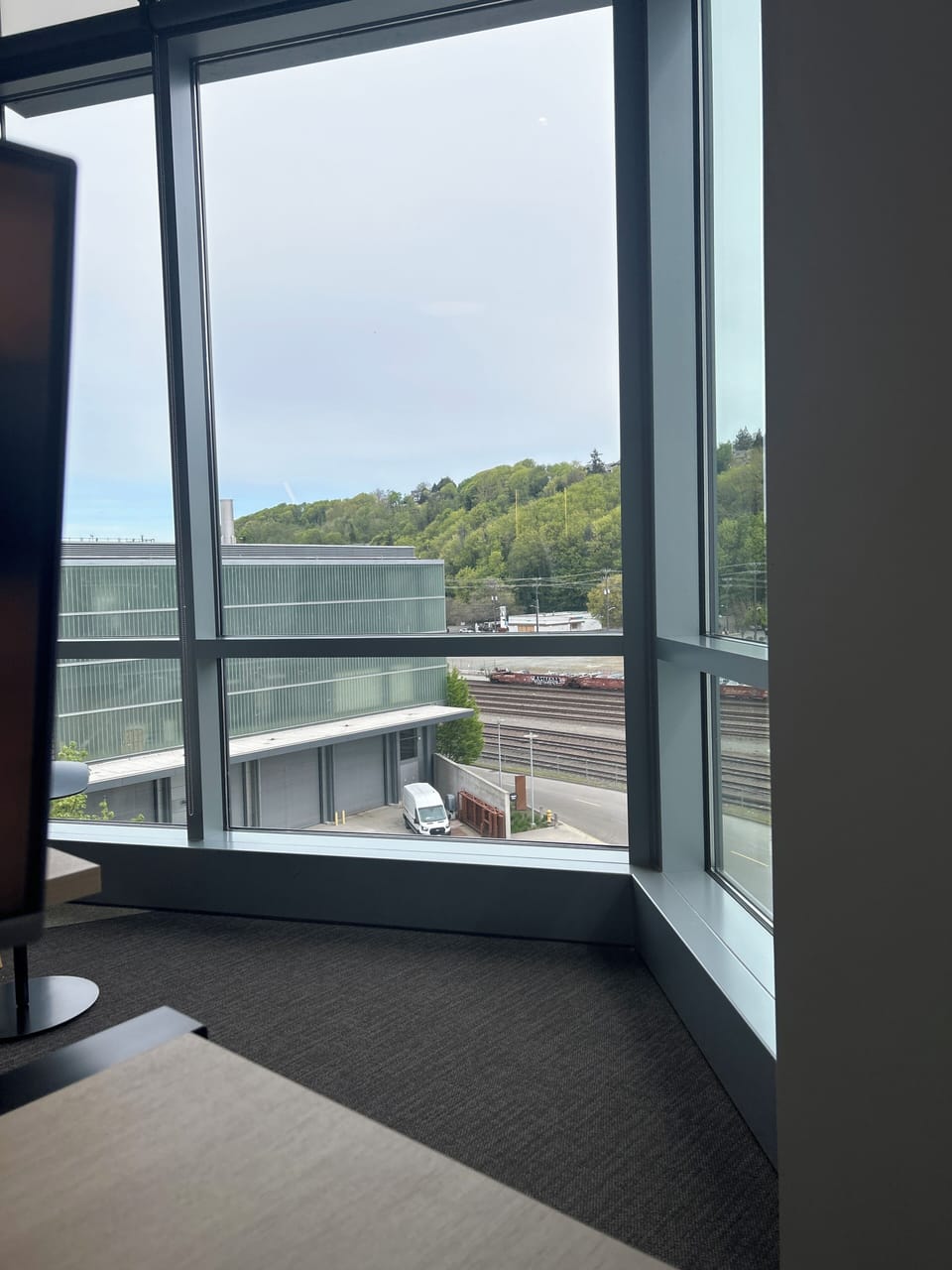 Large window overlooks trees and modern building