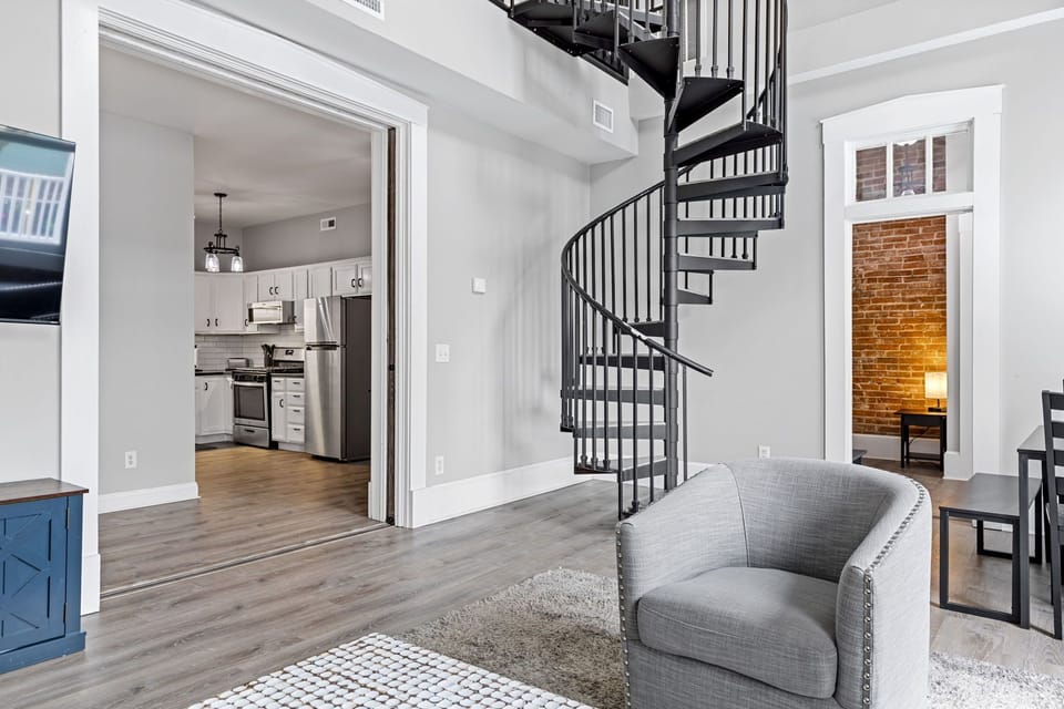 This open-plan view shows the easy flow between the living room, kitchen, and spiral staircase.