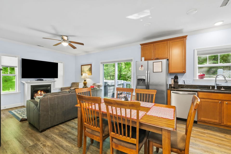 Dining area overlooking the kitchen and living room with natural light from large windows. Open floor plan provides easy gathering space near downtown Bryson City.