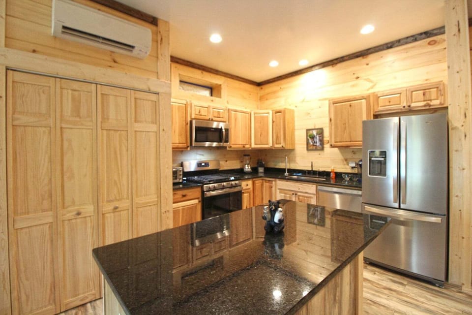 Spacious kitchen showcasing wood cabinetry, granite surfaces, and stainless appliances. Cabin rental near Smoky Mountain adventures.