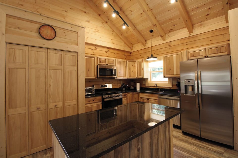 Fully equipped kitchen featuring granite countertops, stainless steel appliances, wood cabinetry, and center island. Guests have everything needed for preparing meals during their Bryson City stay.