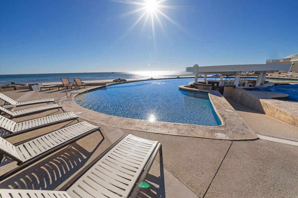 Spacious sun deck with loungers, pool, and beach views all in one.