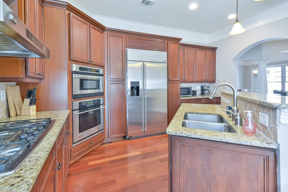 The kitchen is a modern, spacious, and well-designed area with white cabinets, a large island, and essential appliances, offering a bright and inviting atmosphere for meal preparation and enjoyment.The kitchen is a modern, spacious, and well-designed area