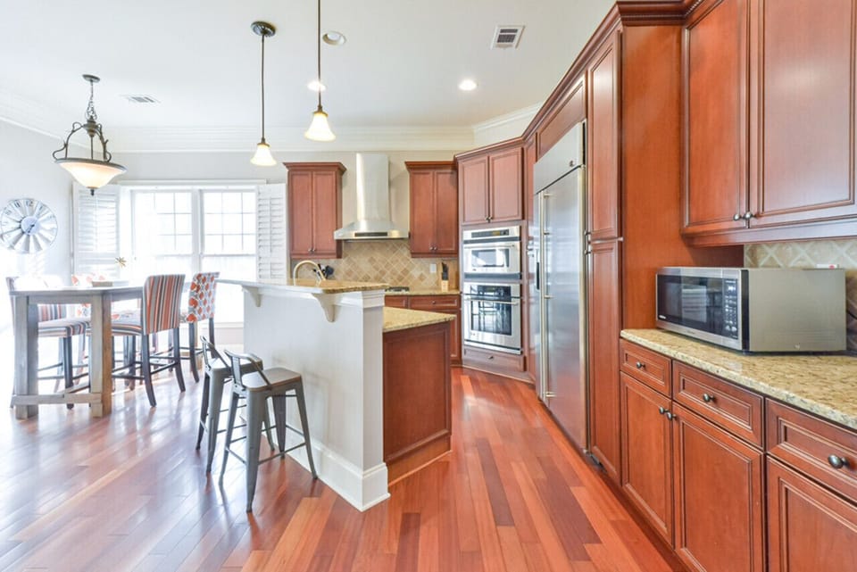 The kitchen is a modern, spacious, and well-designed area with white cabinets, a large island, and essential appliances, offering a bright and inviting atmosphere for meal preparation and enjoyment.