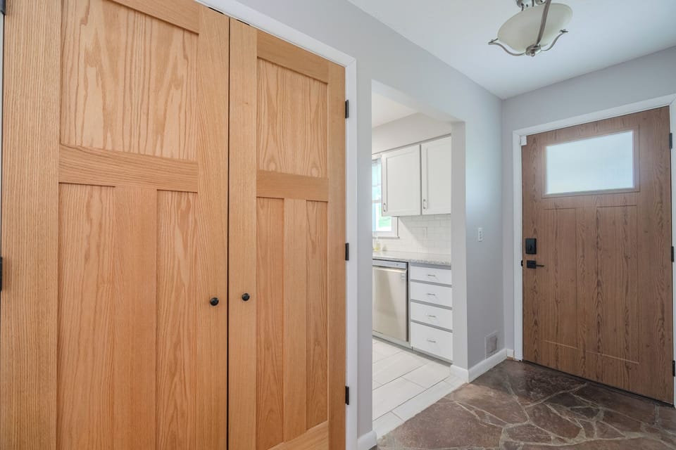 Entryway with front door and hidden laundry closet featuring washer and dryer.