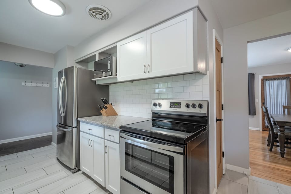 Electric stove, microwave, full fridge, and spacious layout for meal prep.