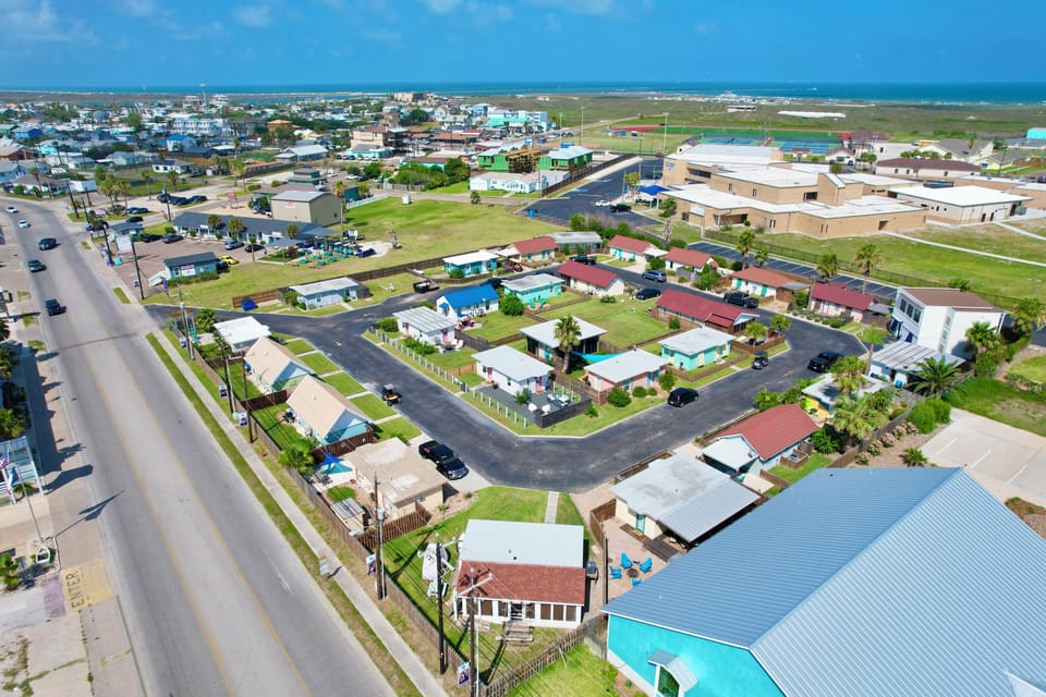 Aerial view of a coastal neighborhood featuring residential properties near the ocean with well-maintained streets and green spaces.