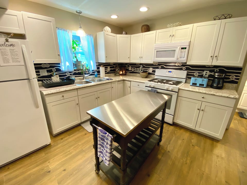 Well appointed kitchen. Pots, pans, plates, cups, silverware, spices, stocked.