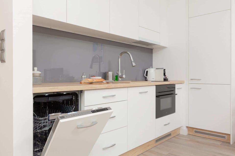 A kitchen with white cabinetry, a built-in oven, and ample counter space, blending functionality with a simple aesthetic.