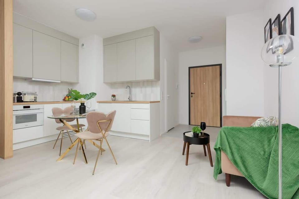 A sleek kitchen and dining area, with light wood cabinets and a minimalist table adorned with fresh greenery, designed in a clean and open layout.