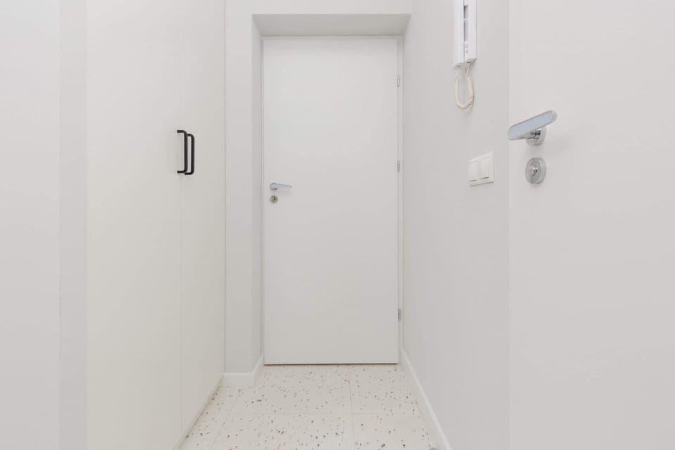 Bright hallway with white walls and spacious wardrobe.