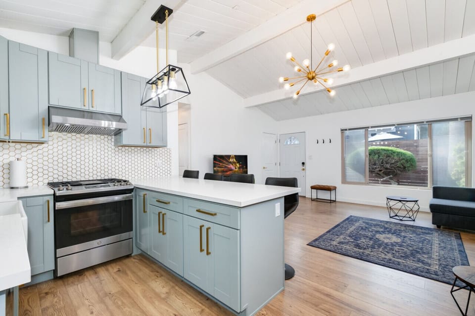 Stylish open-plan kitchen and living area with modern appliances, a spacious island, and contemporary lighting, offering a perfect space for cooking and socializing