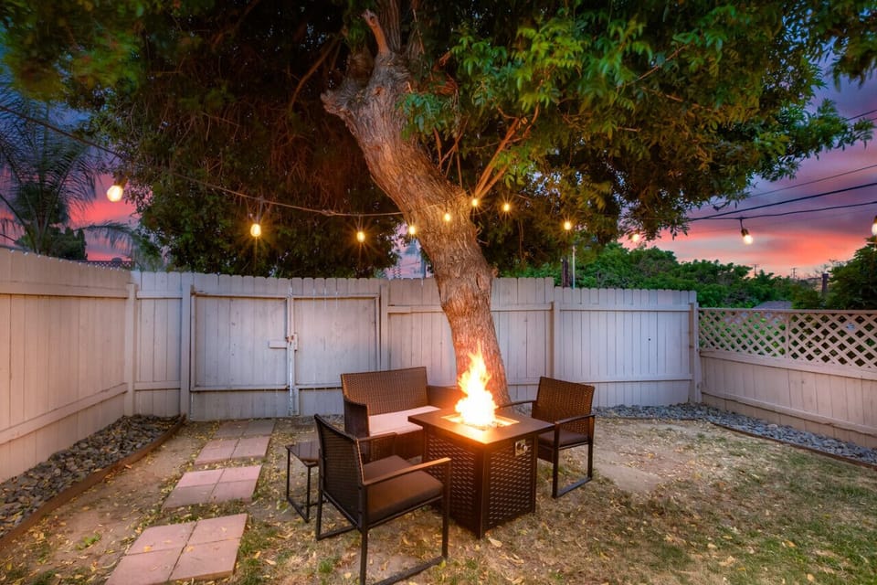 Cozy backyard at sunset with string lights and a fire pit, perfect for enjoying a warm and inviting atmosphere in the evening.