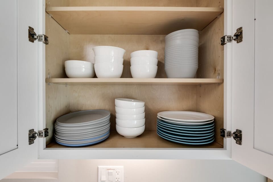 Well-stocked kitchen cabinet with plates, bowls, and serving dishes