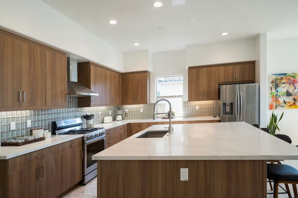 Contemporary kitchen w/ warm wood cabinetry & expansive island