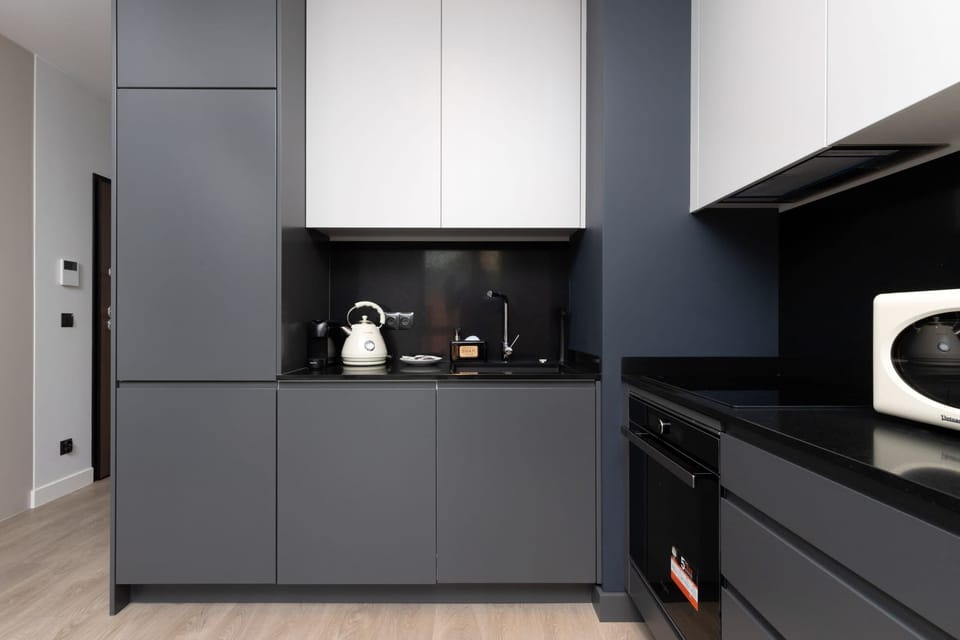 A kitchen with sleek black cabinetry, a built-in oven, and ample countertop space.