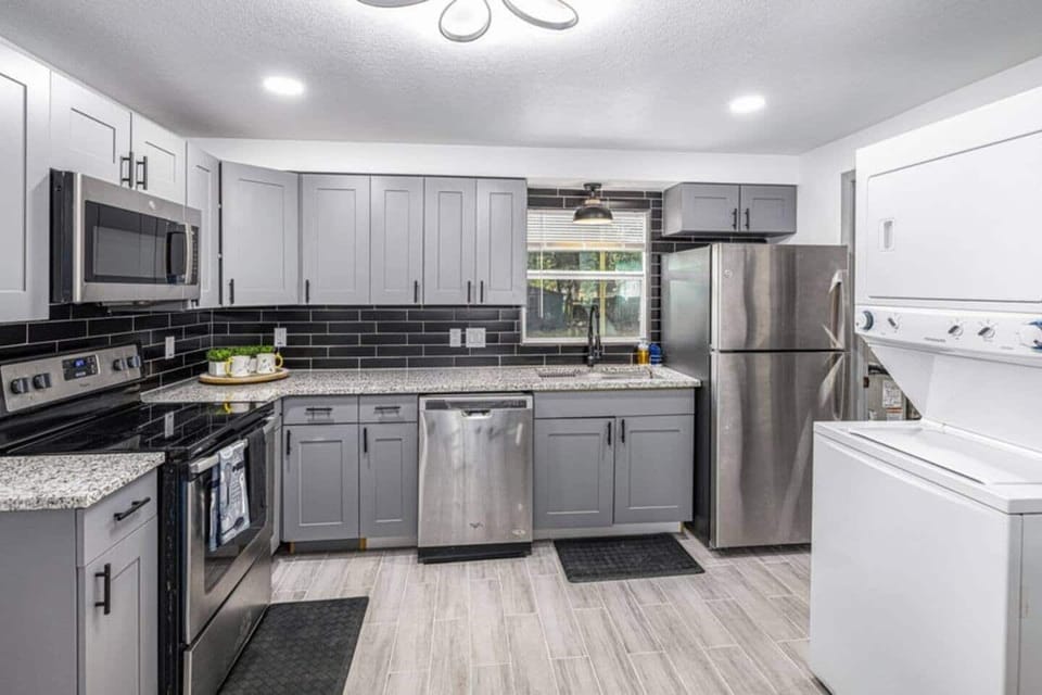 The kitchen is equipped with spacious cabinets, a 4-burner stove with an oven, a microwave, and a large refrigerator. It also features a convenient laundry area with a washer and dryer