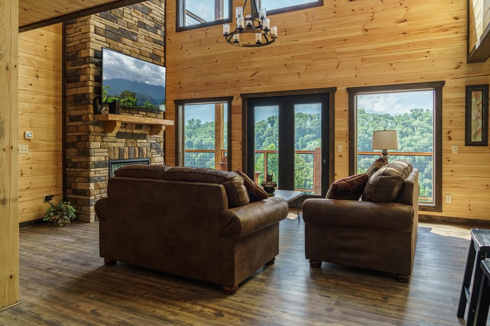 Two story living area with floor to ceiling stone fireplace and smart tv. 
