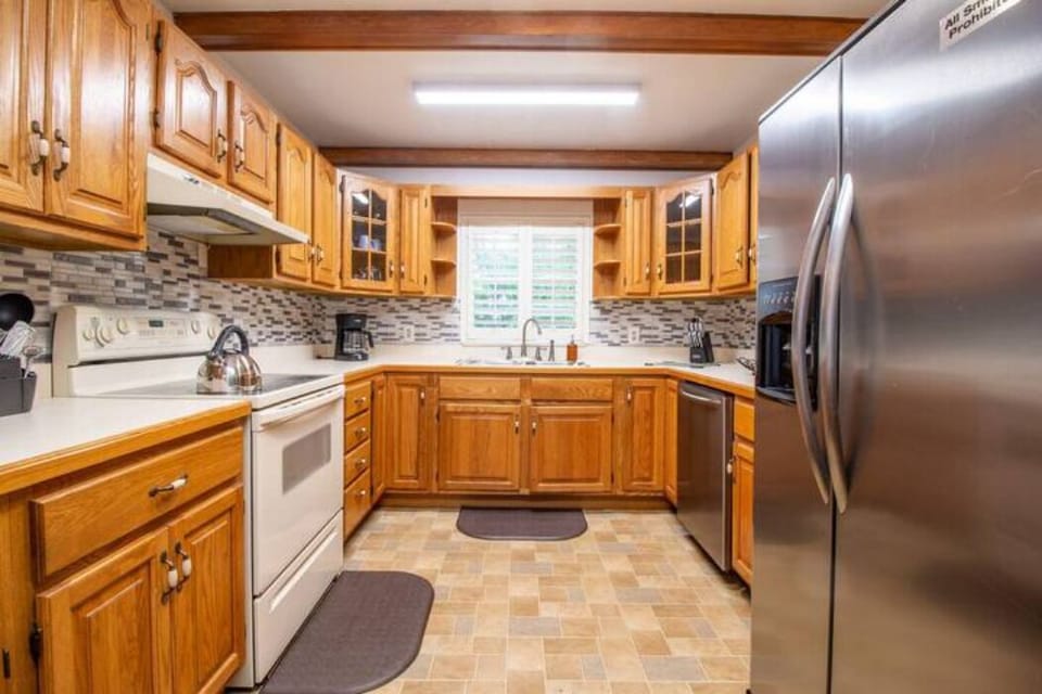 kitchen with four-place stove, kettle, coffee maker, large refrigerator and elegant cabinetry
