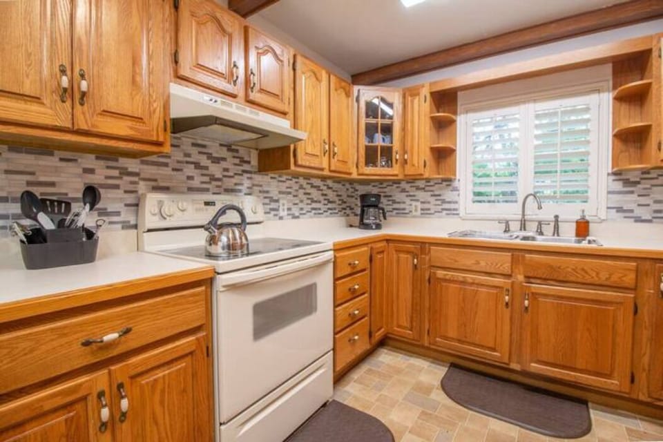 kitchen with four-place stove, kettle, coffee maker, large refrigerator and elegant cabinetry
