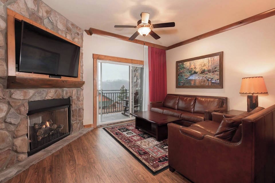 Spacious Living Room features a fireplace, queen sleeper sofa, TV, and door to a private balcony..