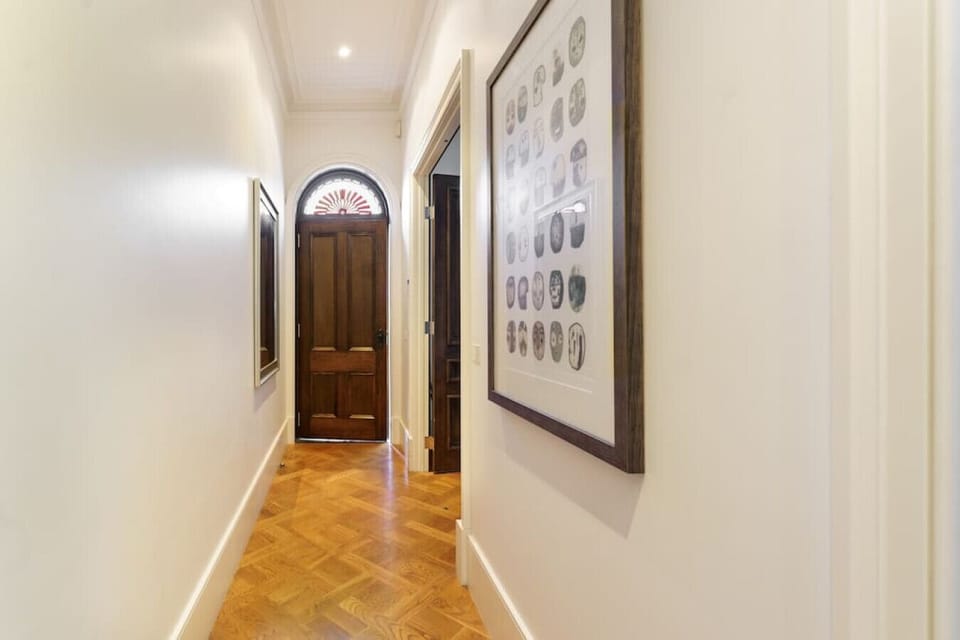 [Hallway] Wooden front door with art frames on the wall.