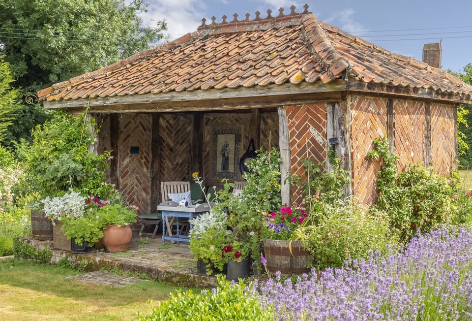 The medieval-style summer house has garden furniture to relax in at Ayres End Studio, Suffolk