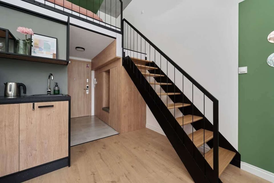 Stairs leading to the bedroom with a green-painted wall and framed minimalist artwork above the bed.