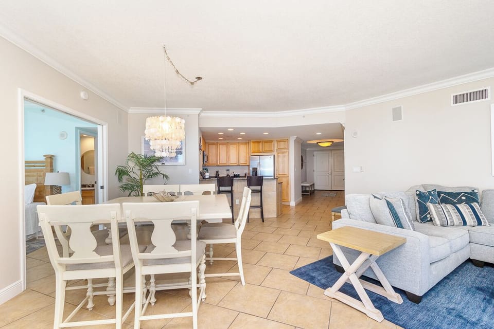Relax in your spacious open-concept living area featuring elegant dining space, fully equipped kitchen, and comfortable seating with coastal-inspired décor.