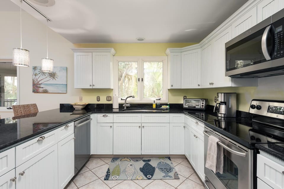 The kitchen sits off the main living room. This space has been updated with stainless appliances, granite counter, and an open bar area.