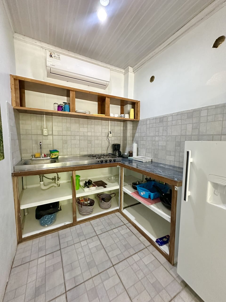 Kichen with medium fridge, 4 burner stove top, coffee maker and pots and pans.