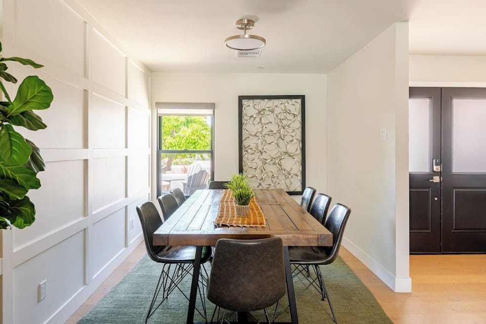 Gather around this warm, wood-accented dining table that seats eight—perfect for family meals or game nights. Natural light pours in from the window, bringing the outdoors in.