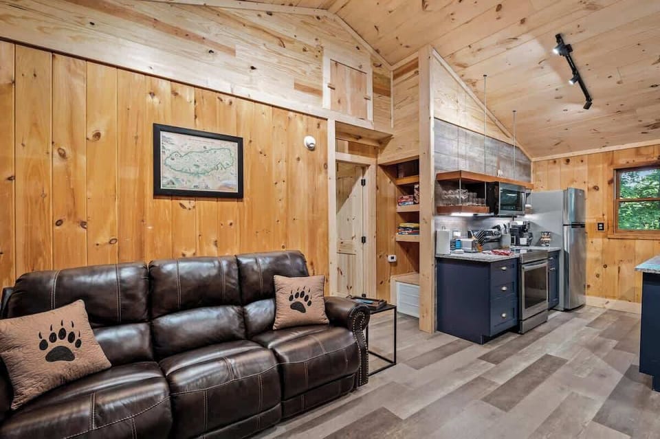 Comfortable open-concept living space with a plush leather sofa, cozy cabin vibes, and easy access to the fully equipped kitchen.