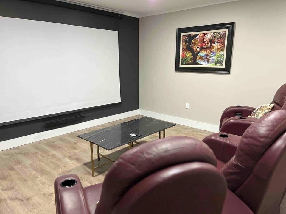 Private movie room with large screen, leather recliners, and streaming capabilities.